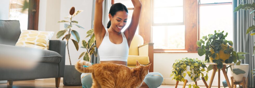 Mujer con top blanco feliz con un gato naranja, gracias al servicio de cuidado de mascotas de Mamaju.