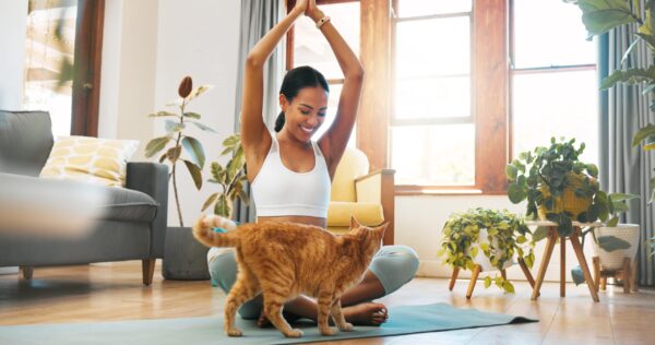 Mujer con top blanco feliz con un gato naranja, gracias al servicio de cuidado de mascotas de Mamaju.